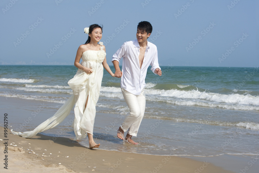 Happy newlyweds running on the beach