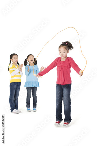 Two girls cheering their friend as she jump ropes