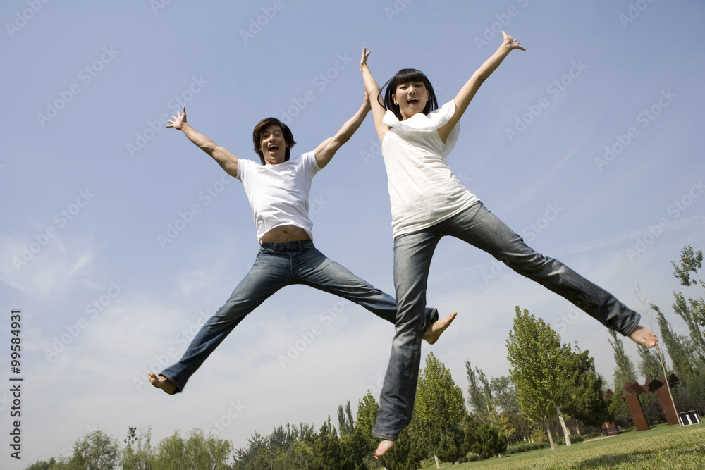 Young couple jumping in mid-air Young couple jumping in mid-air