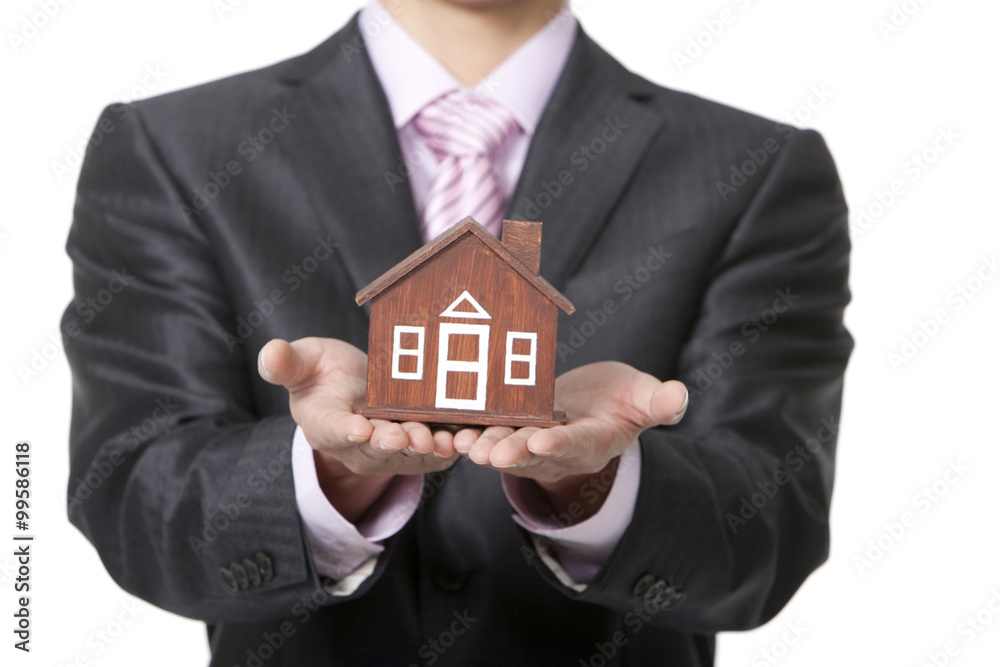 Businessman holding a small wooden model home Businessman holding a small wooden model home