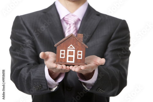 Businessman holding a small wooden model home
