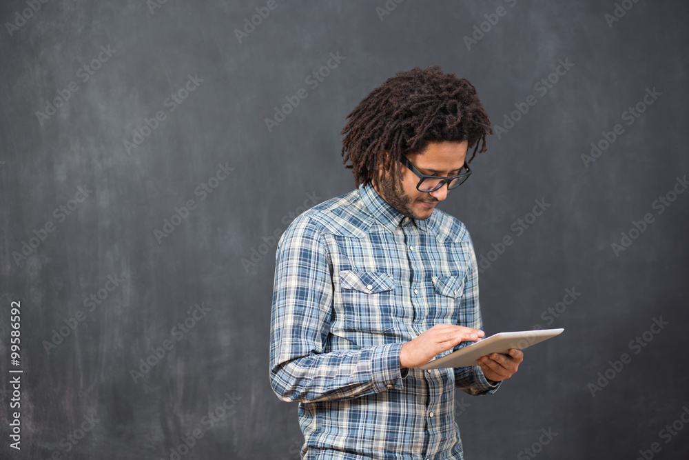 Enjoying his digital tablet. Cheerful young African man holding Enjoying his digital tablet. Cheerful young African man holding