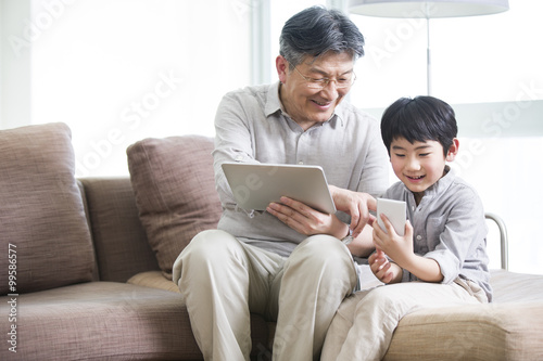Happy grandfather and grandson with digital tablet and smart phone