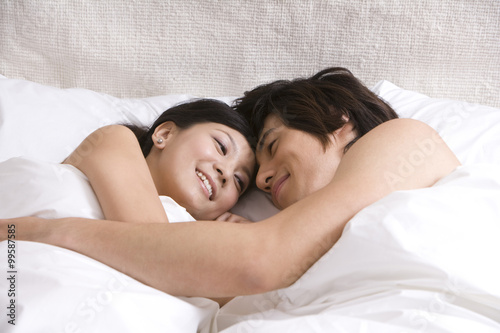 Canvas Print Asian couple cuddling on bed