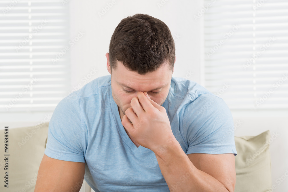 Man With Headache Pinching His Nose At Home Man With Headache Pinching His Nose At Home