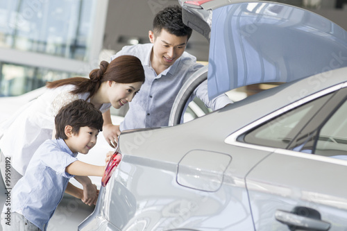 Young family looking at new car in showroom