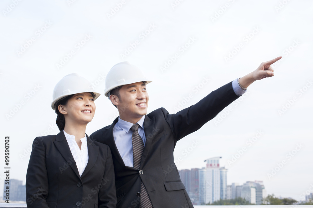 Confident young architects pointing and looking at view outdoors Confident young architects pointing and looking at view outdoors
