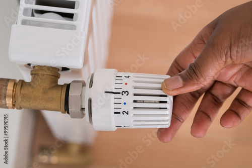 Person's Hand Adjusting Radiator Temperature photo