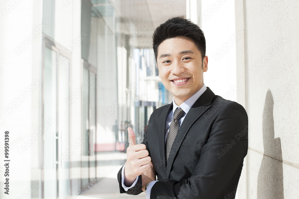Portrait of happy businessman doing thumbs up in downtown district Portrait of happy businessman doing thumbs up in downtown district