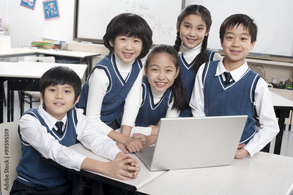Students gathered around a computer in the classroom Students gathered around a computer in the classroom