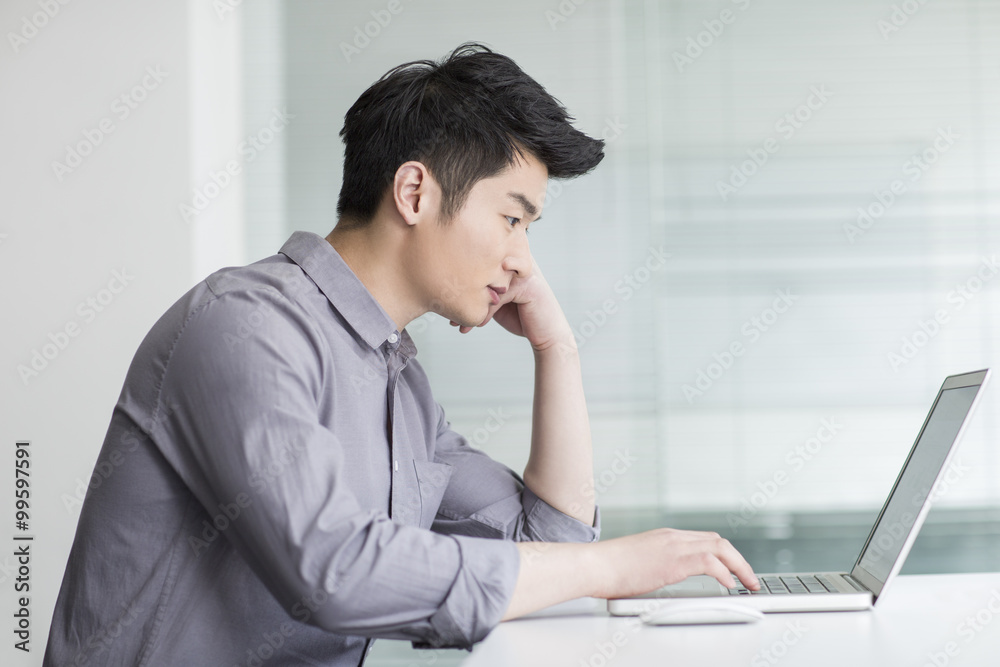 Young businessman using laptop in office Young businessman using laptop in office