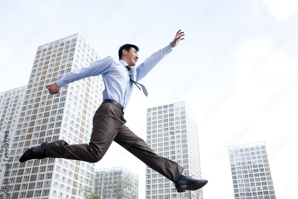Excited young businessman jumping in mid-air Excited young businessman jumping in mid-air
