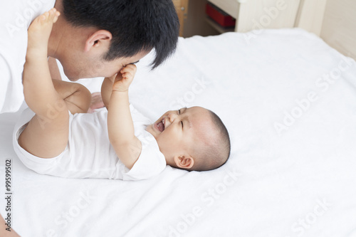 Chinese father and son playing in bed