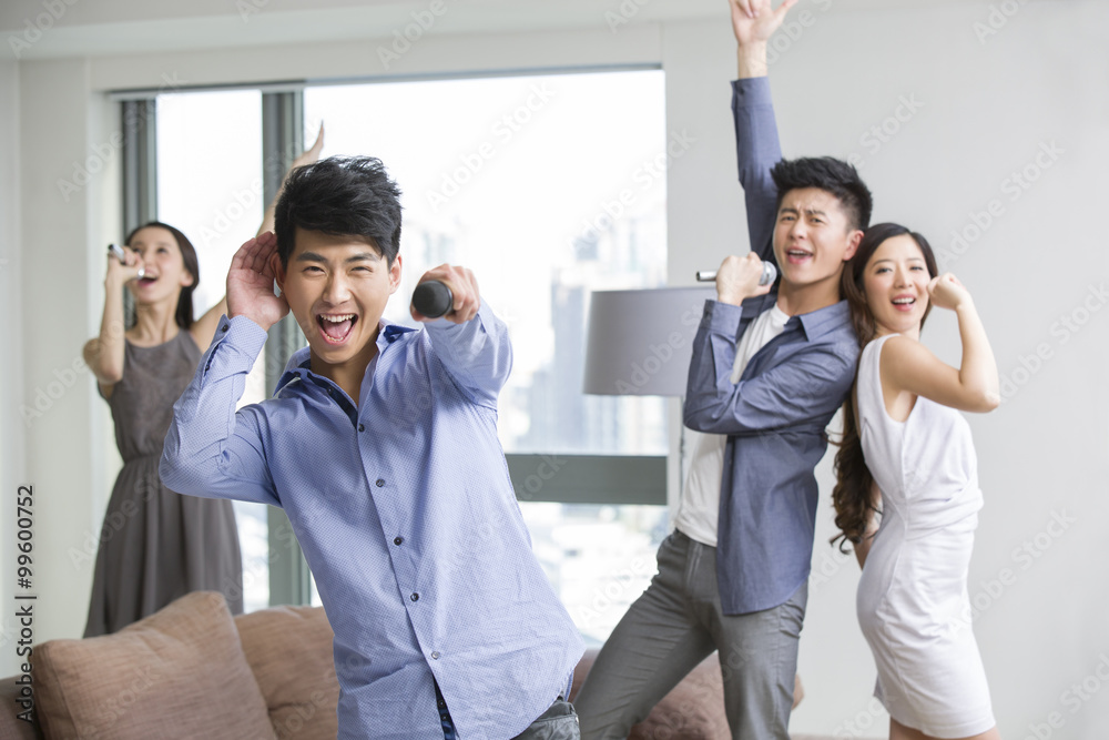 Obraz premium Happy young friends singing and dancing in living room