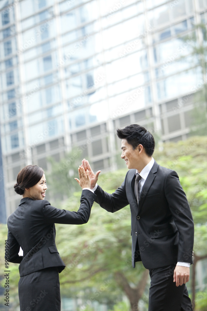 Excited business coworkers doing high-five outside a building, Hong Kong Excited business coworkers doing high-five outside a building, Hong Kong
