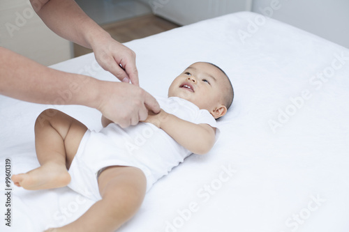 Chinese father taking care of a baby in bed
