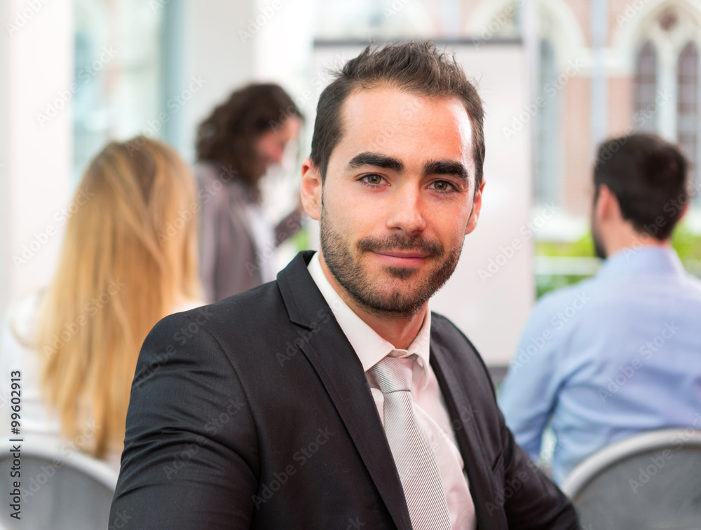 Young attractive businessman working at the office with associat Young attractive businessman working at the office with associat