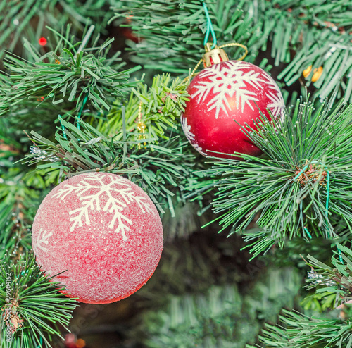 Christmas tree ornament, globe hanging, sparkles, green tree, snow flakes, bells, snowman, lights, close up.