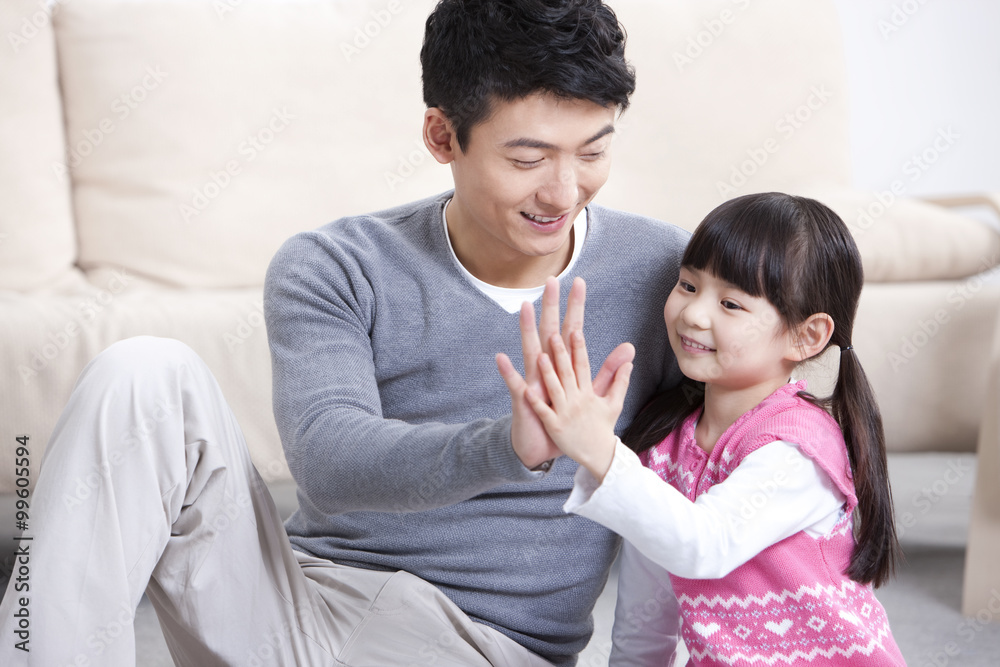 Happy father and little daughter doing high-five at home Happy father and little daughter doing high-five at home