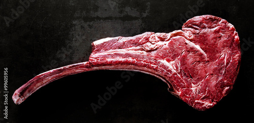 Uncooked tomahawk steak on black