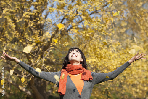 Happy young woman enjoying golden fallen leaves