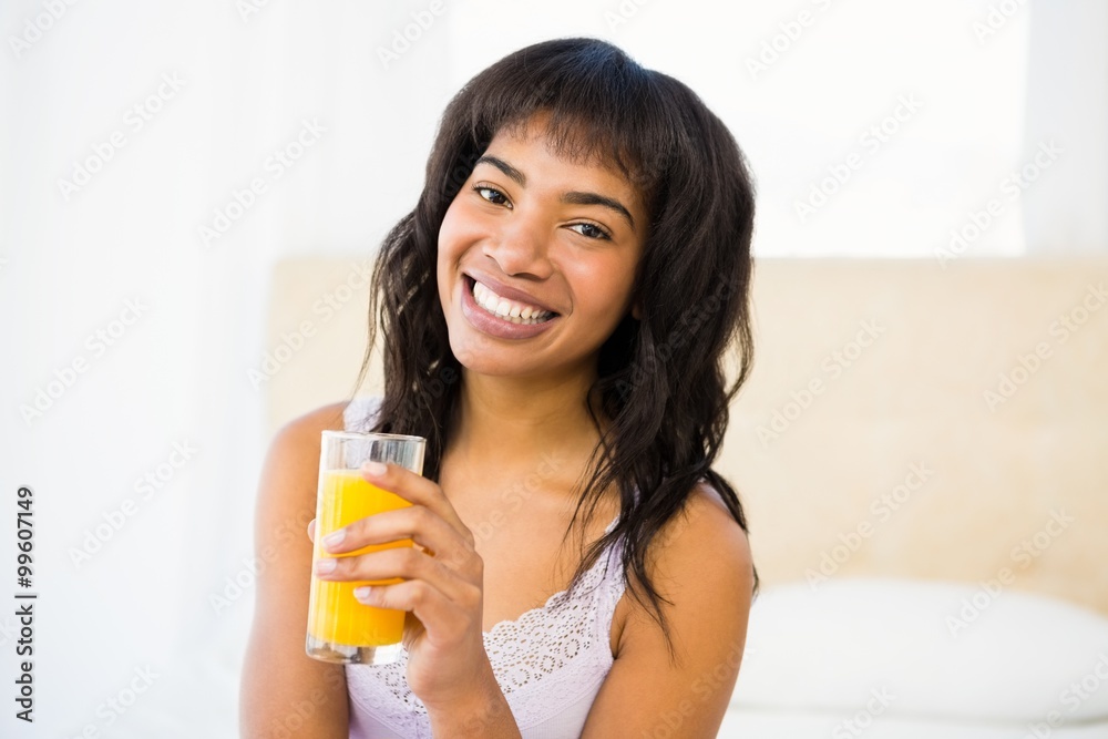 Casual smiling woman holding a glass of orange juice Casual smiling woman holding a glass of orange juice