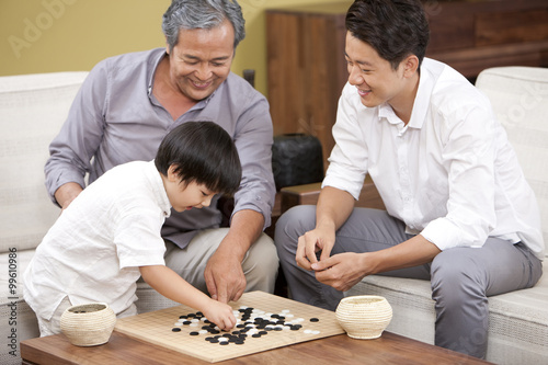 Three generations of men playing Chinese game of Go