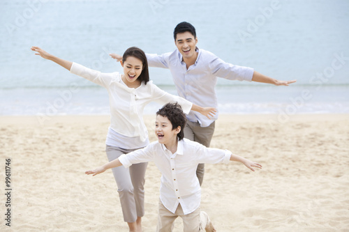 Joyful young family pretending to be flying on the beach of Repulse Bay, Hong Kong © Blue Jean Images