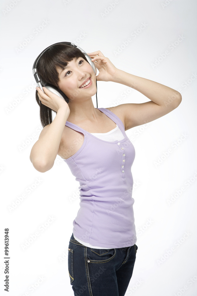 Naklejka premium Smiling young woman listening to music on headphones