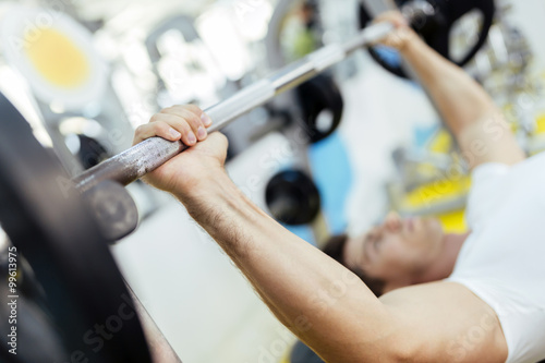 Handsome man lifting weights in gym