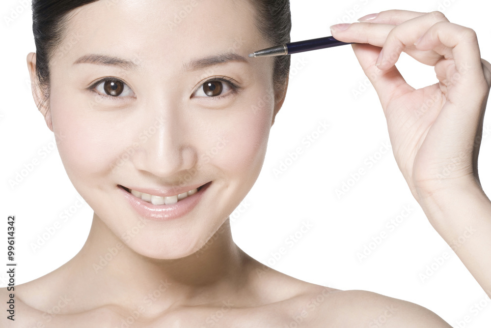 Beauty shot of a young woman penciling eyebrow