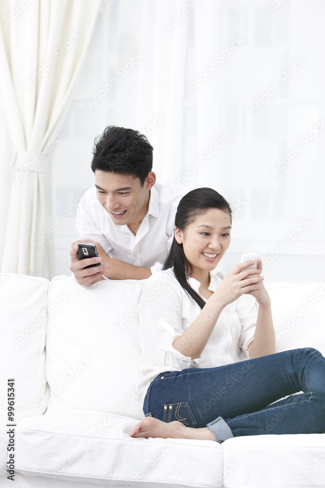 Couple using phones together at home Couple using phones together at home