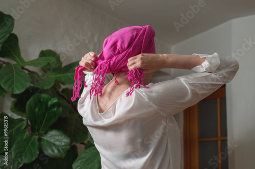 Fotografía Woman ties a kerchief on her head
