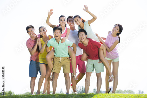 Group photo of cheerful young adults standing on grass