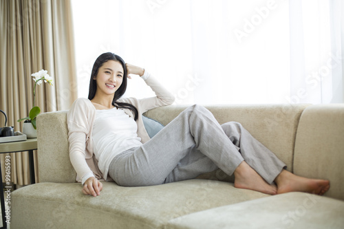 Happy young woman sitting on sofa Free Download Happy young woman sitting on sofa - GFXLoad