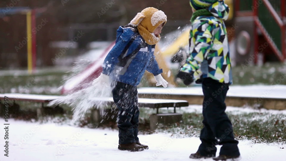 Two boys, brothers, playing in the snow with snowballs, wintertime