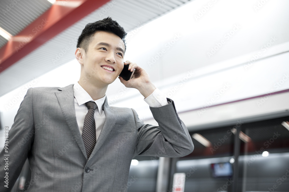 Young businessman on the phone on subway platform Young businessman on the phone on subway platform
