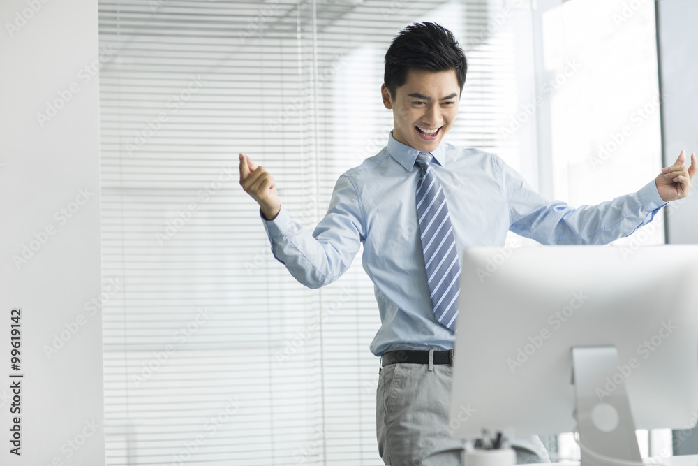 Cheerful young businessman using computer in office Cheerful young businessman using computer in office