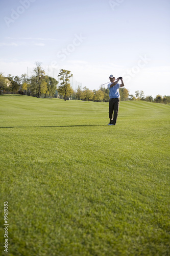 Man swinging golf club on golf course © Blue Jean Images