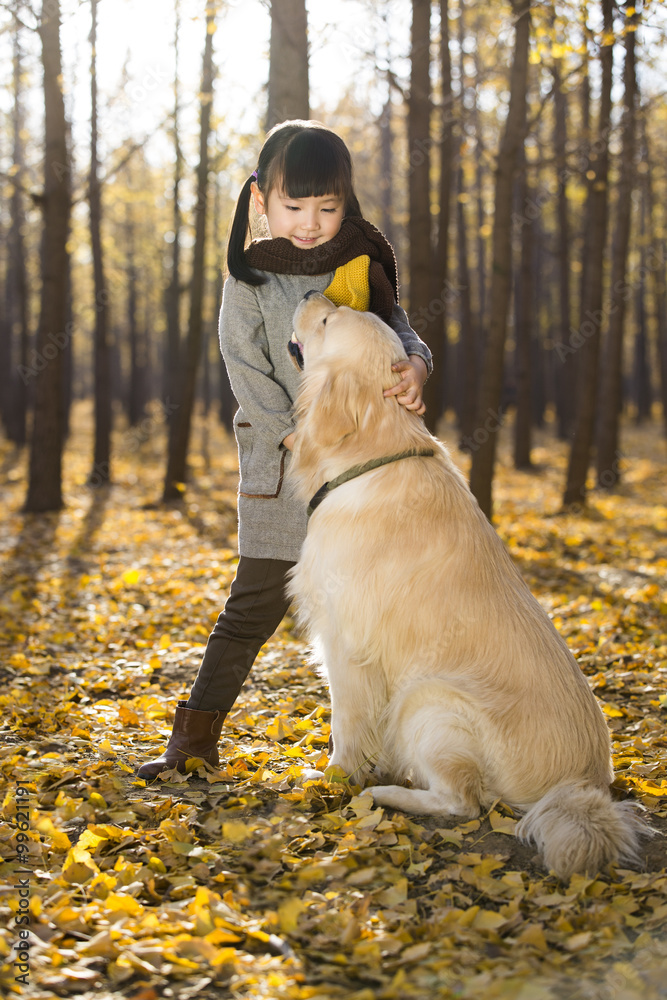 Little girl playing with dog in autumn woods