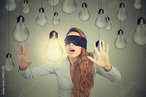 Photos Blindfolded young woman walking through lightbulbs searching for bright idea