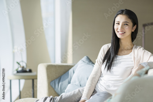 Happy young woman sitting on sofa