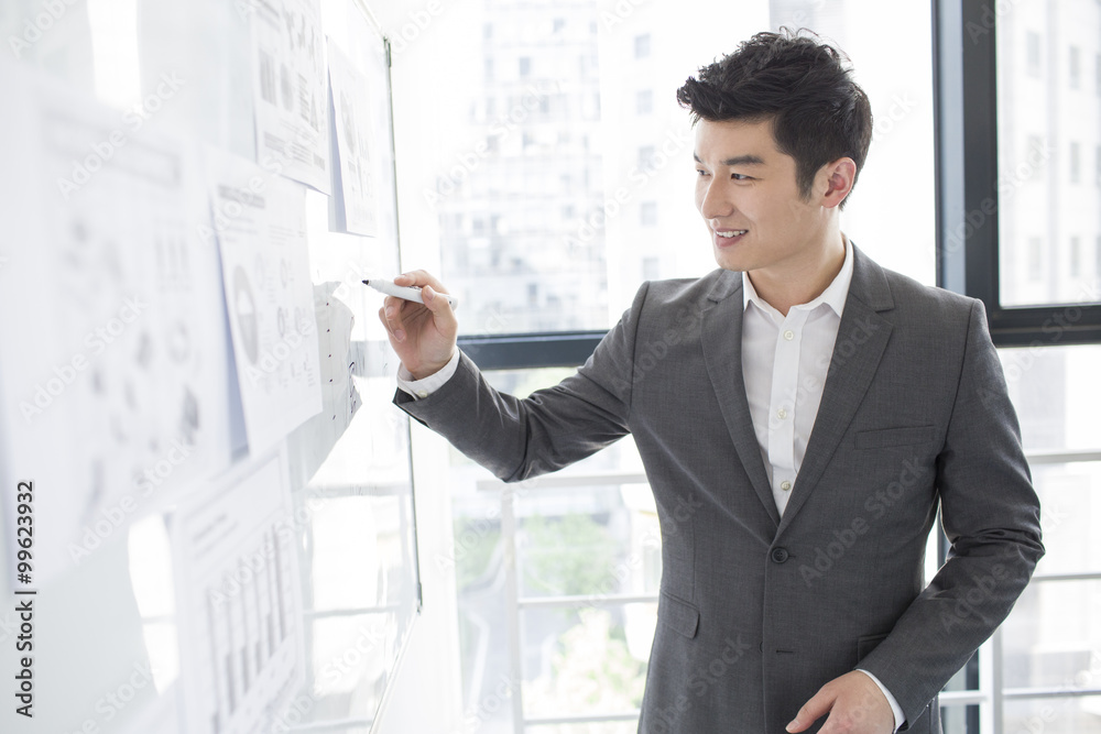 Young businessman writing on whiteboard in the office Young businessman writing on whiteboard in the office