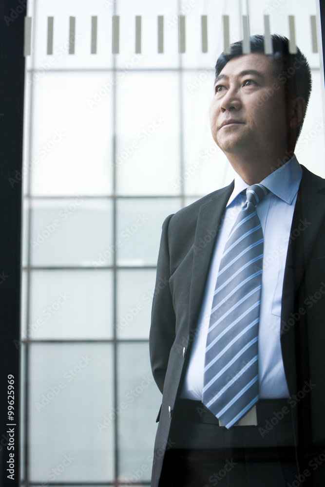 Businessman deep in thought through glass window Businessman deep in thought through glass window