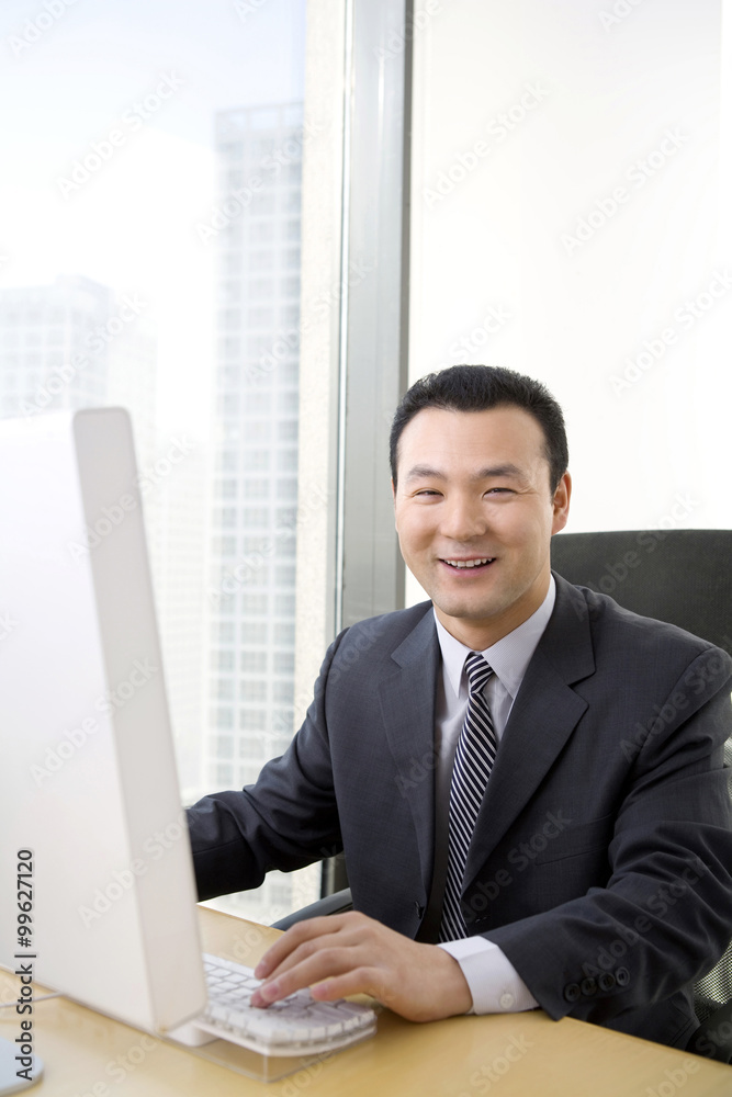 Fototapeta premium Man uses computer in a well-lit, sunny office