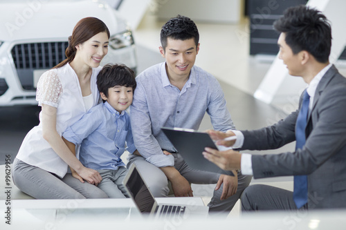 Young family buying car in showroom