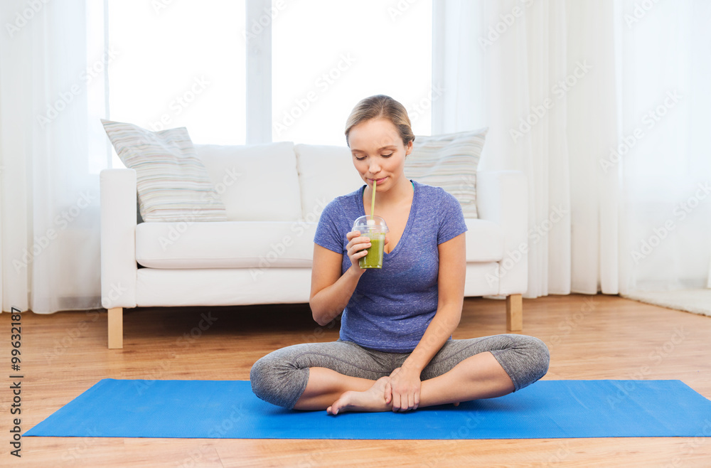 happy woman with smoothie sitting on mat at home happy woman with smoothie sitting on mat at home