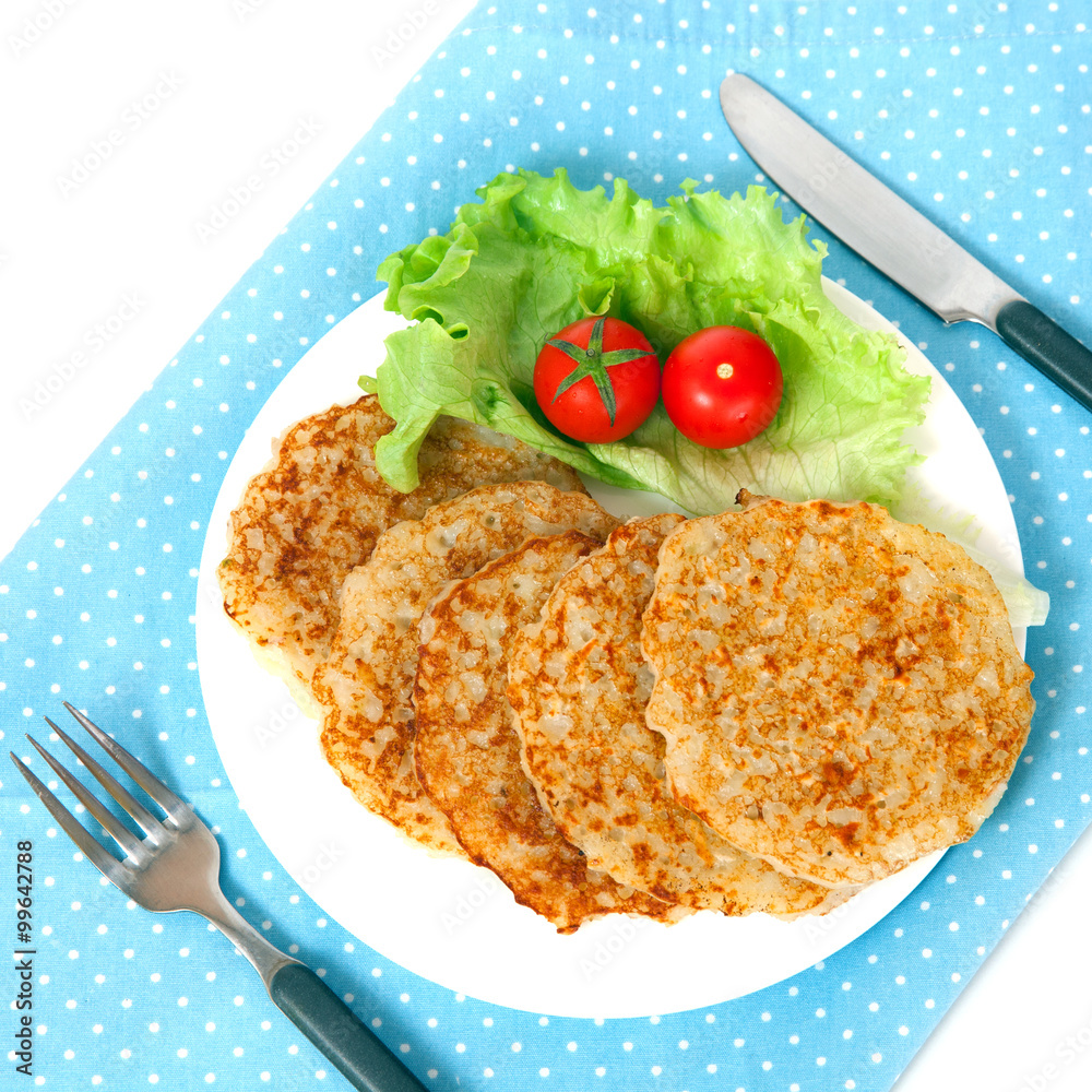 A potato pancakes with lettuce and tomatos on blue napkin