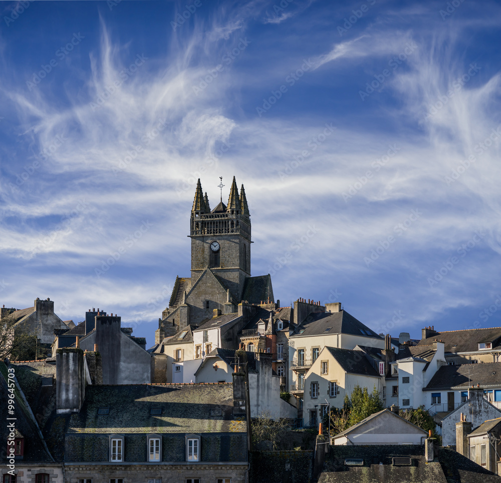 La ville Quimperlé en Bretagne avec l'église Saint Michel devant un ciel avec des nuages cirrus