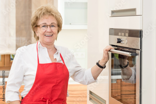 Hausfrau steht lächelnd am Backofen